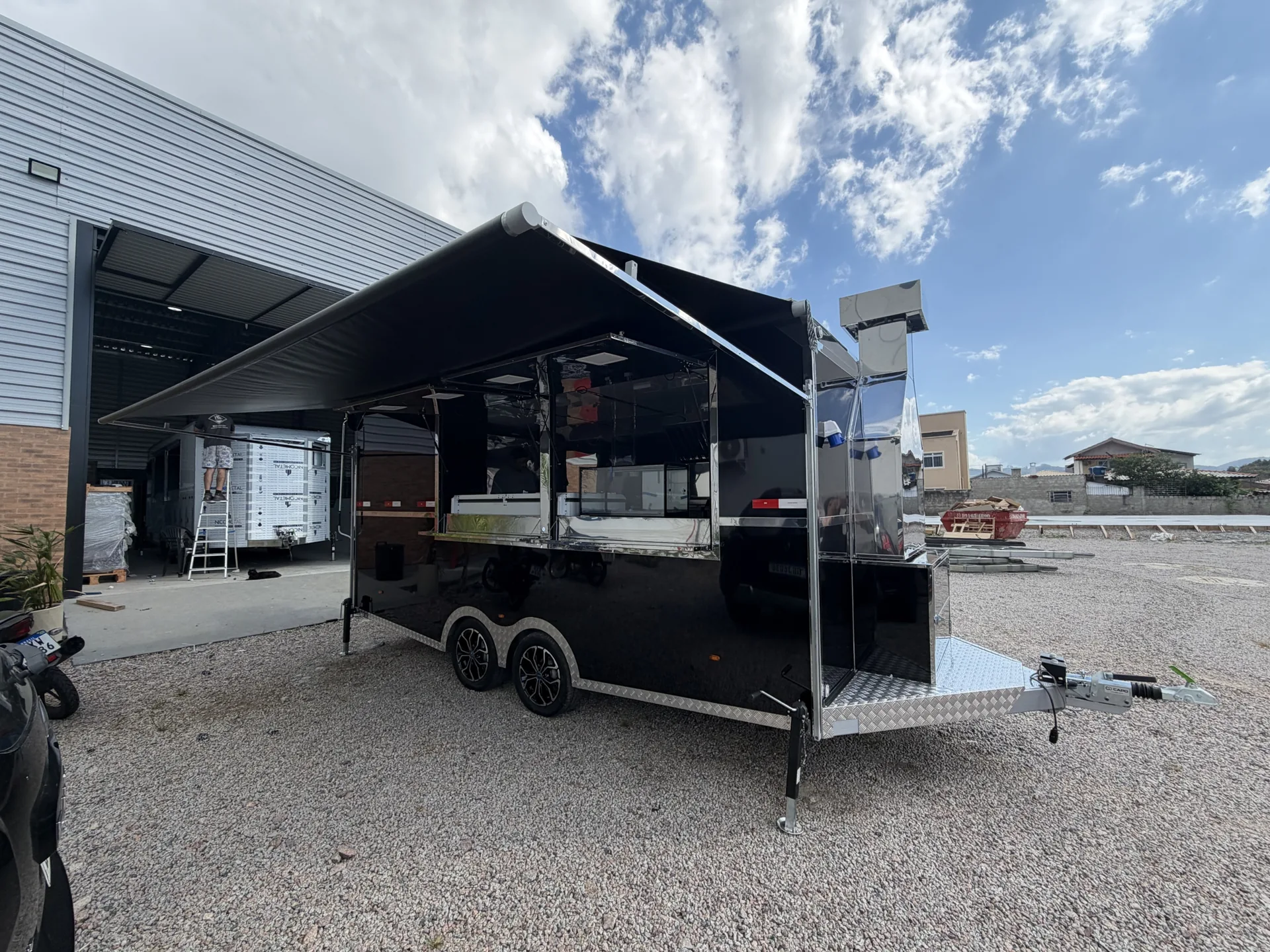 Food truck preto com toldo aberto e cozinha em inox visível